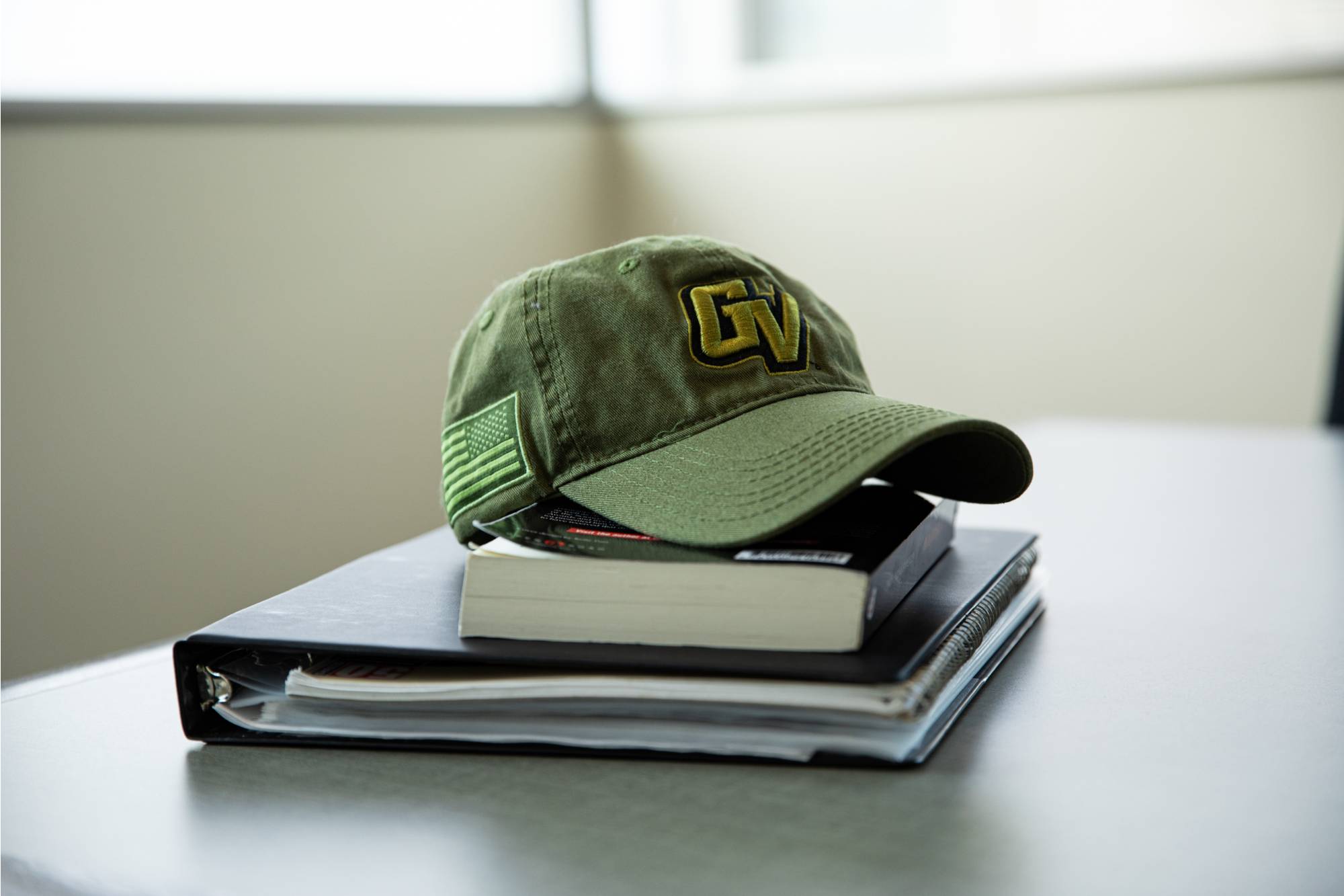 GVSU Hat on a stack of textbooks